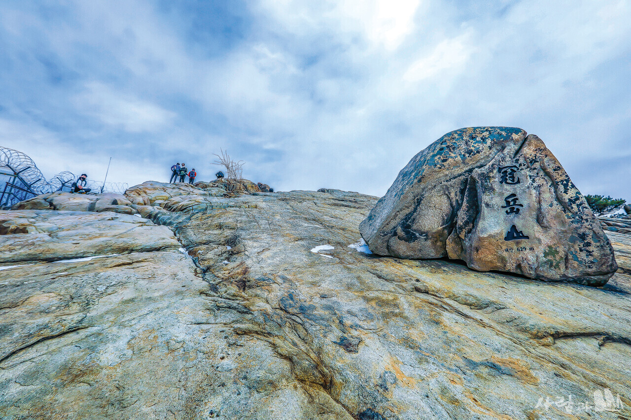 관악산 정상. 수십 명이 앉을 수 있는 비스듬하고 널찍한 암반 위에 자연석 정상석이 놓여있다.